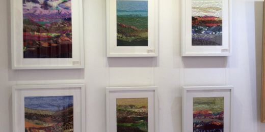 A gallery wall displays six framed artworks, primarily depicting abstract landscapes with varied colors and textures. Each piece features a blend of vibrant shades and intricate patterns, inviting viewers to explore the artistic interpretations of natural scenery.